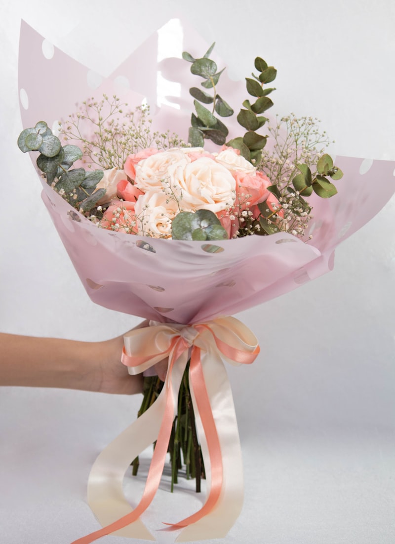 Ramo en tonos rosa envuelto en papel, listo para regalar